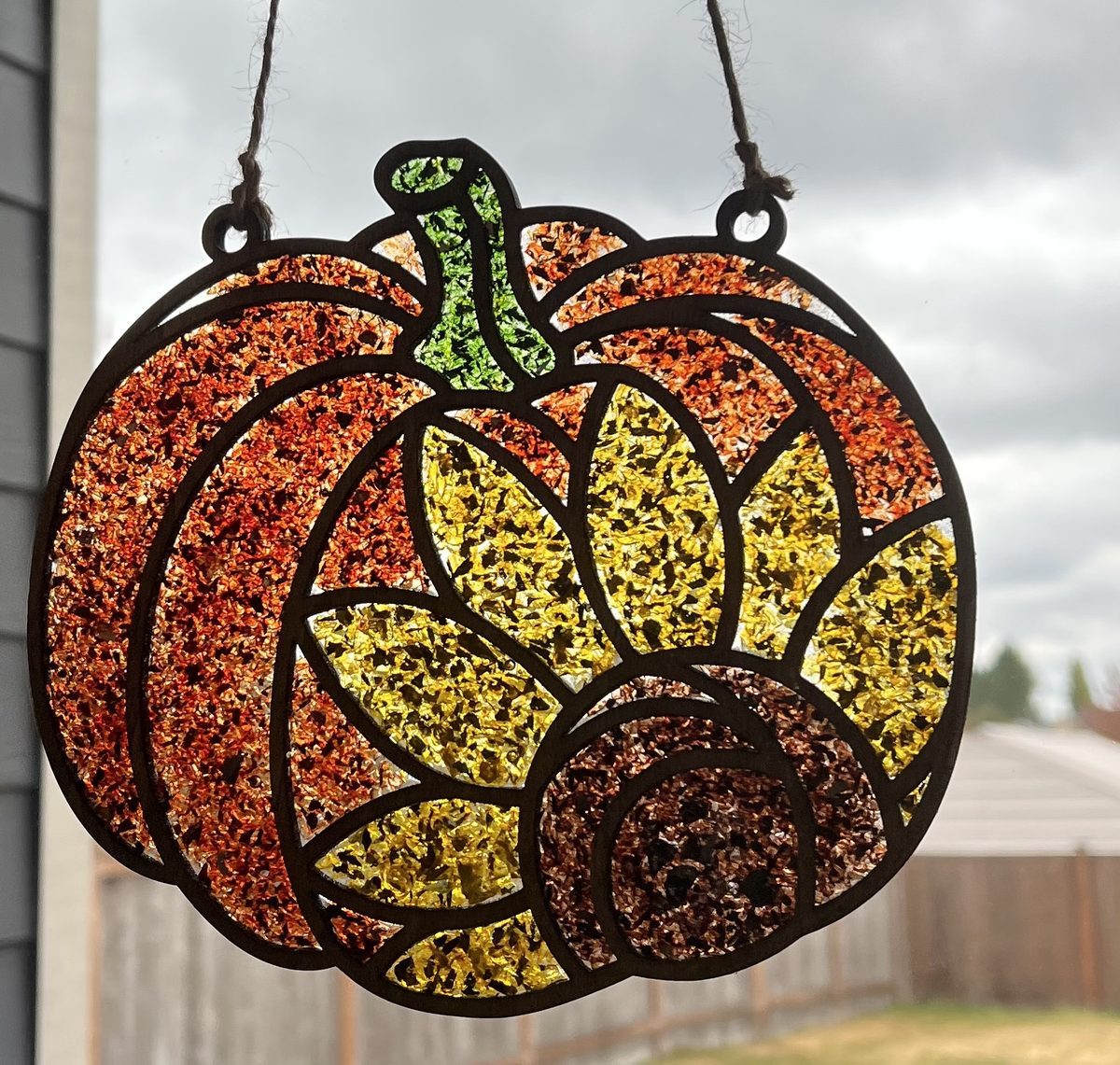 Handmade crushed glass pumpkin and sunflower suncatcher hanging in a window